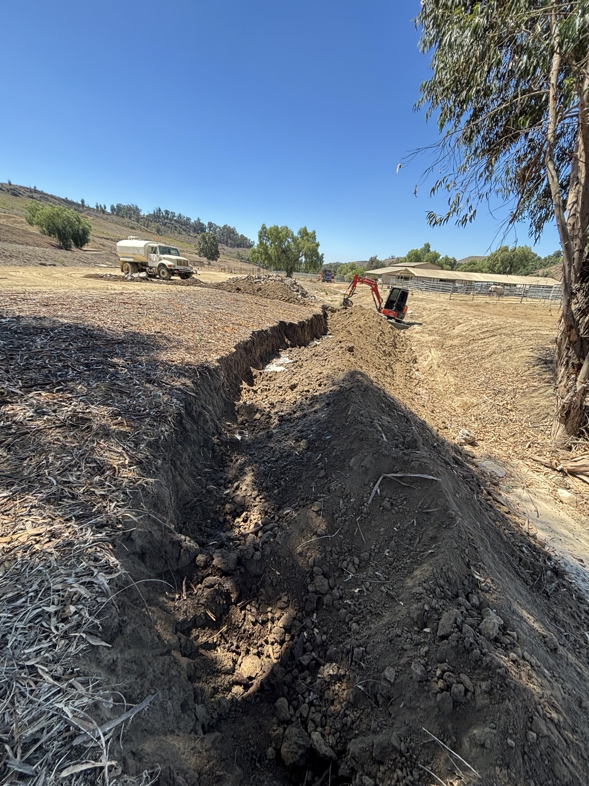 Long excavated trench with an excavator on site